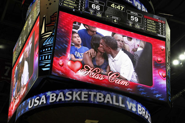 US President Barack Obama and first lady Michelle Obama are shown kissing on the 'Kiss Cam' screen during a timeout in the Olympic basketball exhibition game between the US and Brazil national men's teams in Washington, July 16, 2012. Obama cheers for US Olympic basketball team