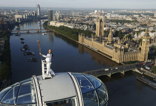 Torch bearer Amelia Hempleman-Adams, age 17, stands on top of a capsule on the London Eye as part of the torch relay ahead of the London 2012 Olympic Games in London July 22, 2012. Torch bearer stands on top of London Eye