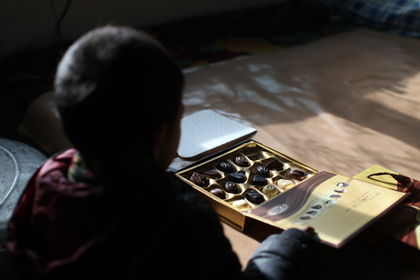 The grandson of Tang Rongbin receives a box of chocolate as a gift in Luotuowan village, Fuping County, Dec 31, 2013. Poor village gets $48 million after Xi's visit