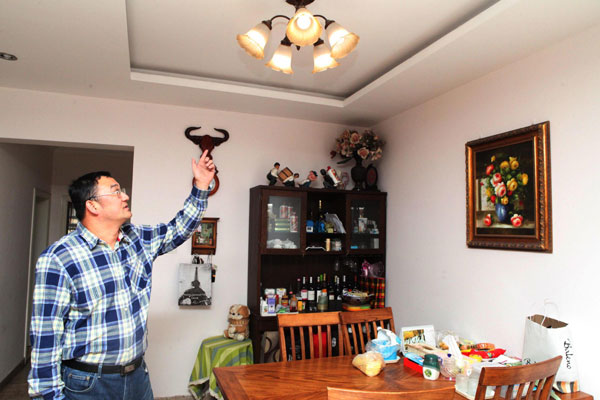 Dong Qiang points to a lamp that uses electricity generated from one of his solar panels in Tianjin, April 6. Self-generated electricity may be sold in Tianjin