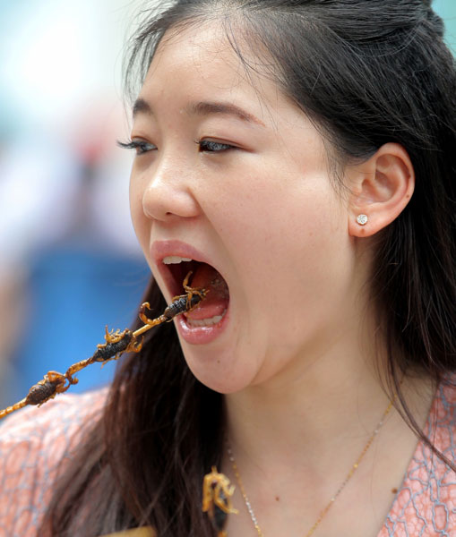 Duan Ying, 24, samples fried scorpion in Wangfujing, Beijing. WANG JING / CHINA DAILY Nation not ready for insect diet, expert warns