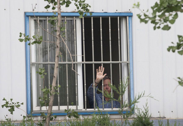 American Chip Starnes, co-owner of Specialty Medical Supplies, waves from a window of an office where he says he’s been “kidnapped” by Chinese workers inside his plant on the outskirts of Beijing, June 24, 2013. US factory boss held hostage in Beijing
