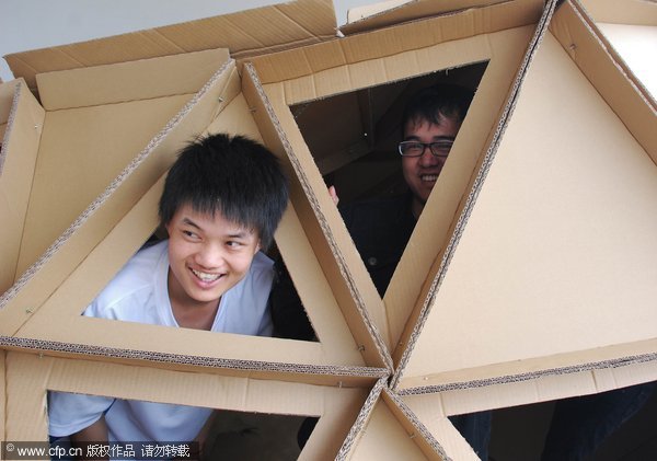 Huang Jinlong, team leader of a competition group, smiles while inside a football-like building during a 'Low emission, Green Living' campaign in Fujian Engineering College, Fuzhou, south China's Fujian province on May 10,2011. 'Green living' paper buildings stand in college