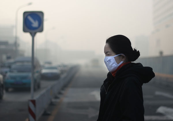 A resident wearing a mask and sunglasses walks in Beijing, as heavy smog hit the city on Tuesday. Wamg Jing / China Daily Thick smog grounds flights and fouls air