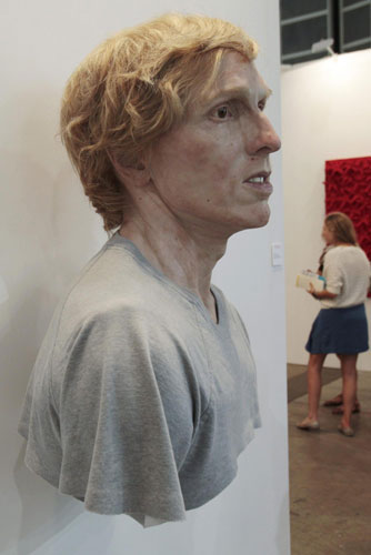 A woman stands next to a sculpture titled 'Young Self' by Canadian artist Evan Penny at the Hong Kong International Art Fair May 25,2011. HK welcomes world's leading galleries