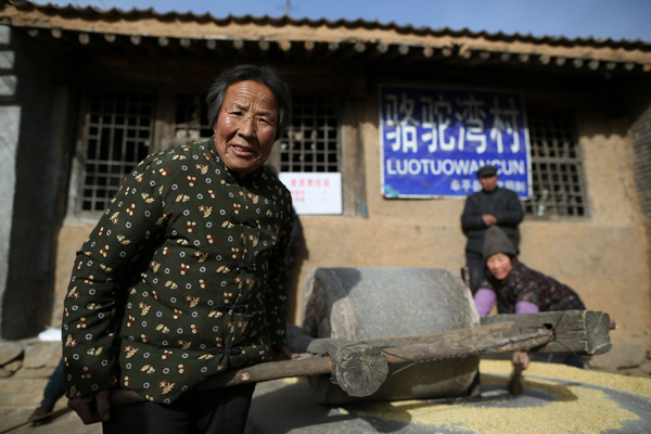 Villagers grind soybeans at a yard in Luotuowan village, Fuping County, Dec 31, 2013. Poor village gets $48 million after Xi's visit