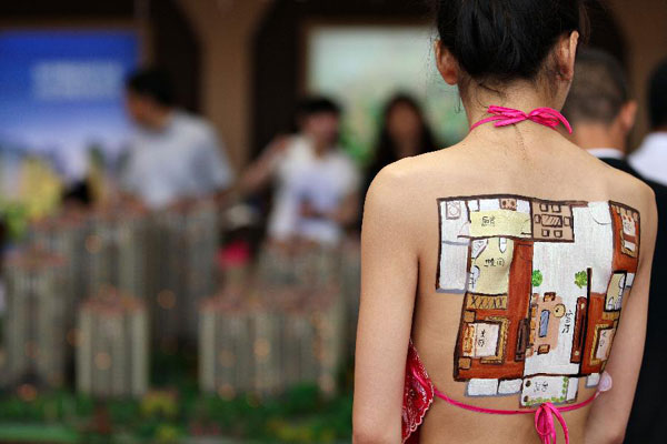 A model has her back painted with layout drawings of a house as a method to attract customers during the 55th Housing Fair held in Nantong city, East China's Jiangsu province, May 24, 2013. New ways to sell a house?
