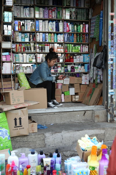 A vendor plays with her cellphone at a market in Shenyang, Northeast China’s Liaoning province, Oct 9, 2013. When smartphones attack