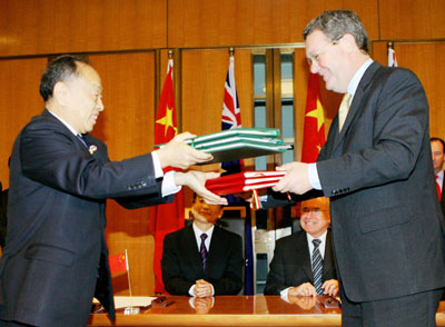 Chinese Premier Wen Jiabao (back L) and Australian Prime Minister John Howard (back R) watch foreign ministers Li Zhaoxing (L) from China and Alexander Downer from Australia exchange the Nuclear Safeguard Agreement during a signing ceremony in Canberra's Parliament House April 3, 2006.