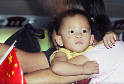 A young Solomon Islander of Hong Kong descent is carried onto a bus after arriving in Guangzhou, southern China's Guangdong province, April 25, 2006. More than 300 Chinese, including some from Hong Kong, board a chartered flight provided by Beijing that evacuated them from the troubled Solomon Islands after they lost all their possessions in the recent riots in Honiara.