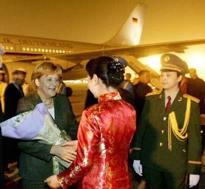 German Chancellor Angela Merkel receives flowers from an unidentified Chinese woman upon her arrival at the airport of China's capital Beijing May 21, 2006. Merkel is on an official two-day visit to China.
