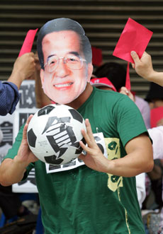 A demonstrator wearing a mask of Taiwan's President Chen Shui-bian and holding a soccer ball with the word which means "corrupt" is shown red cards by other protesters in Taipei, June 13, 2006. Taiwan's parliament launched a motion to oust Chen on Tuesday, turning up the heat on the president over a series of scandals involving his family and former aides.