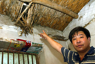 A villager points at the broken roof of his house after an earthquake measuring 5.1 degrees on the Richter scale jolted Wen'an County, north China's Hebei Province at 11:56 a.m. (Beijing Time) Tuesday, July 4, 2006.