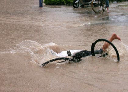 A local resident falls off from his bicycle on a flooded street after a rainstorm hit Fuzhou, east China's Fujian province, July 16, 2006. Torrential rainstorms and flooding unleashed by Typhoon Bilis killed at least 154 people across southeast China, according to latest Xinhua and local news reports. Picture taken July 16, 2006.