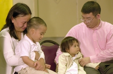 Qin Luo He, left, buries her head on her son, Andy He, 3, as her husband Shaoqiang He, right, holds their daughter, Avita He, 1, prior to a news conference in Memphis, Tenn., on May 12, 2004.