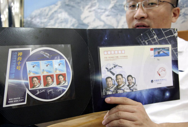A man shows a stamp folder containing an envelope and three stamps with the portraits of three astronauts to be carried by Shenzhou-X, China’s fifth manned spacecraft to be launched Tuesday, June 10, 2013. Stamps commemorating Shenzhou-X manned spacecraft issued