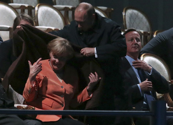 Russia's President Vladimir Putin (C) places a shawl around German Chancellor Angela Merkel as Britain's Prime Minister David Cameron (R) sits before watching a fragment of the ballet 'Ruslan and Lyudmila' during the G20 Summit in Peterhof near St Petersburg, Sept 6, 2013. Musical aqua show during the G20 Summit
