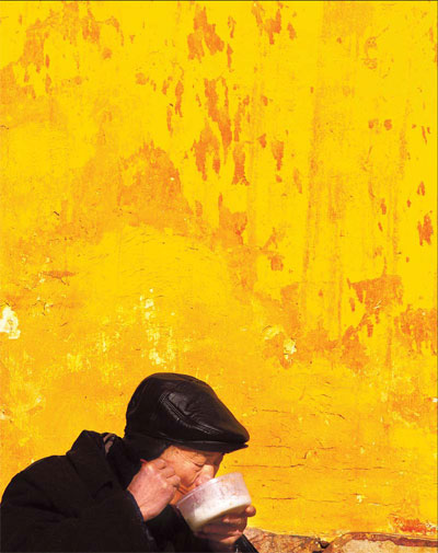 A senior citizen eats lunch beside a temple wall in Nantong, in East China's Jiangsu province. Aging nation creates nursing home boom