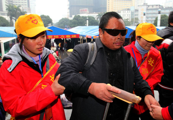 Two volunteers help a blind man enter the waiting hall of Nanning Railway Station in the Guangxi Zhuang autonomous region on Sunday. Huo Yan / China Daily Volunteers ease burden of train travel