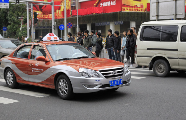 An orange taxi designated for rush hour drives along a street in Guangzhou, Guangdong province, on Tuesday. Some 500 such cabs have been put into service since Tuesday. Zou Zhongpin / China Daily New cabs come to beat rush hour traffic