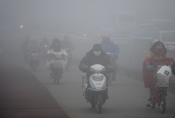 Citizens ride through heavy fog in Nanchang, East China's Jiangxi province, Jan 26, 2013. China issues blue alert for thick fog