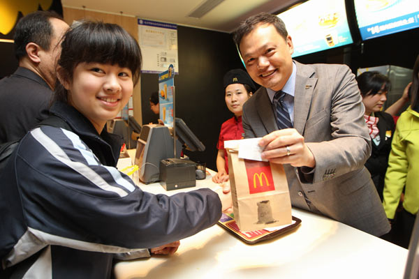 Kenneth Chan,CEO of McDonald's China hands over a bag of Egg McMuffinTM to a customer in a McDonald restaurant in Hangzhou city, East China's Zhejiang province on March 18, 2013, the date of National Breakfast Day. 1.3m breakfast gifts delivered, wonderful Monday to continue
