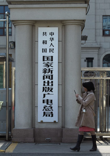 A woman passes by the new sign for the State General Administration of Press, Publication, Radio, Film and Television, March 22, 2013. Reorganized media regulator operational