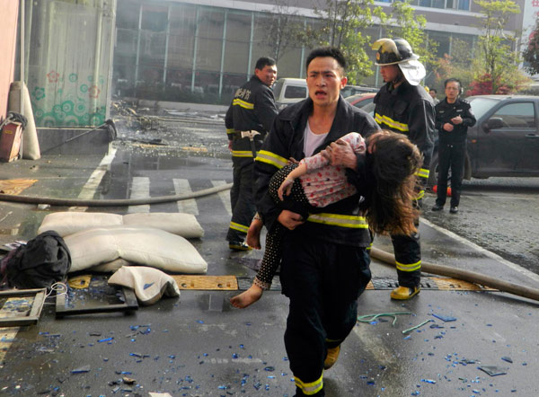 A firefighter rushes a girl out of a fire that killed at least 14 people in Xiangyang, Central China's Hubei province, April 14, 2013. Death toll rises to 14 in central China hotel fire