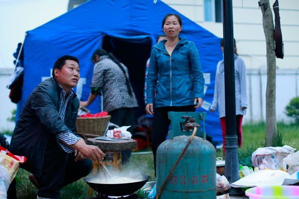 Bai Huaping (left) boils noodles for the rescue team. Feng Yongbin / China Daily Survivors rally to help rescuers