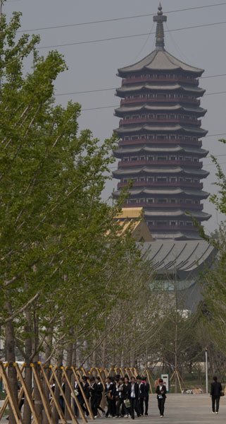Tour guides walk past the Yongding Tower in the Garden Expo site in Beijing on Friday. Beijing's Garden Expo ready for trial run on Sunday