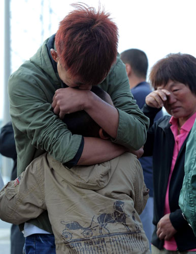 Family members wait in grief on Tuesday for news about relatives the day after a fire engulfed a slaughterhouse at a poultry factory in Dehui, Jilin province. Families cling to fading hopes of finding survivors