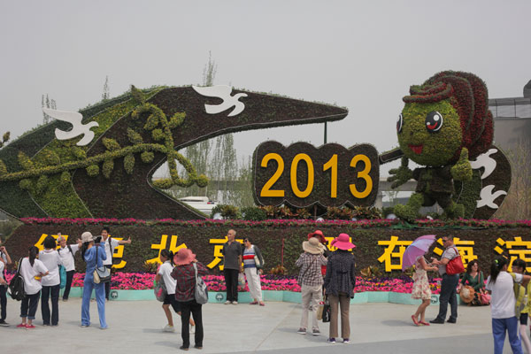 Visitors pose with the mascot of the garden expo before a flower bed. Beijing hosts garden expo
