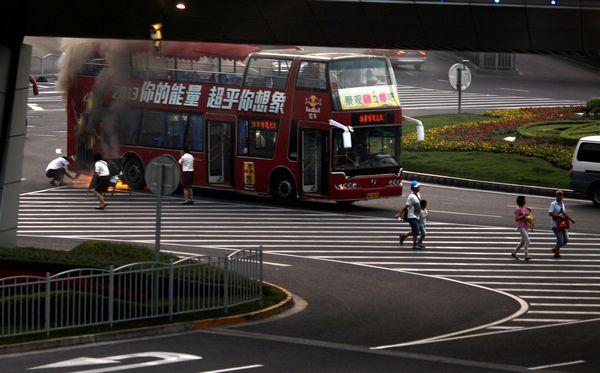 double-decker tourism bus is seen on fire in from of the Oriental Pearl Tower in the Pudong financial district of Shanghai July 8, 2013. Double-decker bus caught fire in Shanghai