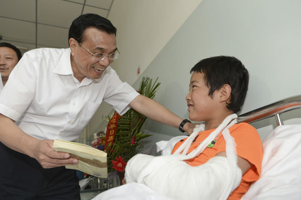 Premier Li Keqiang visits 12-year-old earthquake victim Cao Jiandong in Minxian county, Northwest China's Gansu province, on Saturday. The county was hit by an earthquake on July 22. Premier: Together, we will rebuild