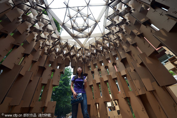 A visitor views houses made of cardboard by Chongqing University students, May 20, 2013. Living paper dreams