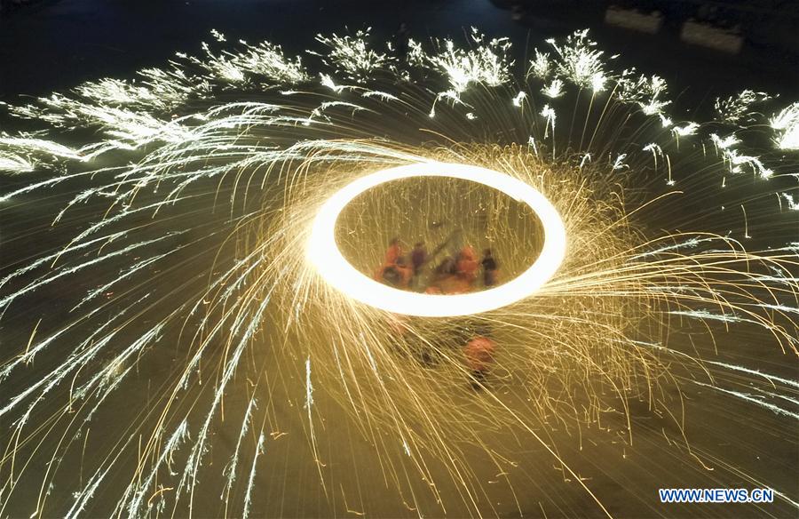 Performers spray burning iron chips to shower sparks-like fireworks