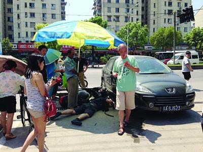 騎車男被卷入轎車輪下 路人抬起轎車救人(圖)