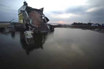 The sun sets for the last time this year behind a building destroyed by Sunday's tsunami in Cuddalore, about 180 km south of Madras December 31, 2004