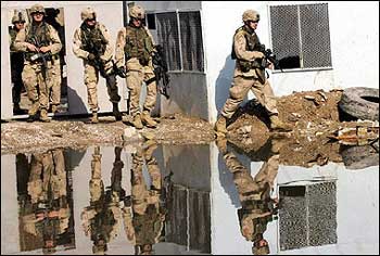 US soldiers are reflected in a pool of rain water as they patrol the notorious Haifa street district, a haven of the insurgency in central Baghdad. Al-Qaeda's frontman in Iraq, Abu Musab al-Zarqawi, declared war on the elections which he said were aimed at bringing the country under Shiite control, in an audiotape posted on an Islamist website. [AFP]
