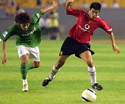 Manchester United's Dong Fangzhou (R) and Beijing Guoan's Zhang Shuai battle for the ball during their friendly soccer match at Workers' Stadium in Beijing July 26, 2005.