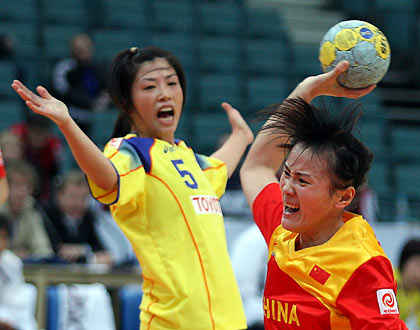 in Wang of China (R) shoots to score as Japan's Mineko Tanaka looks on during their preliminary round match at Women's World Handball Championships in St. Petersburg December 5, 2005.