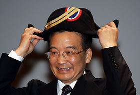 Premier Wen Jiabao puts on the traditional two-cornered hat of the Ecole Polytechnique in Palaiseau, France yesterday. The hat was presented to Wen by students at the prestigious French university. REUTERS