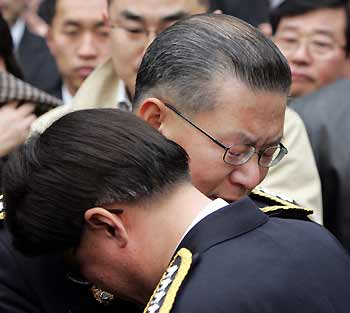 South Korean National Police Commissioner Huh Joon-young (2nd front) hugs his staff member as he leaves the headquarters of the national police agency in Seoul December 30, 2005, after his retirement ceremony.