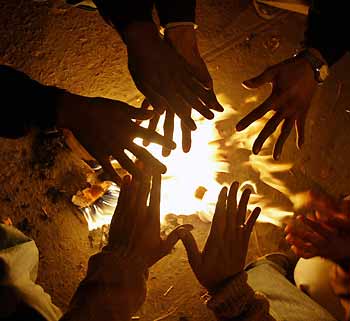 Indian vegetable
sellers warm themselves near a bonfire at a marketplace during a cold wave in New Delhi January 9, 2006.