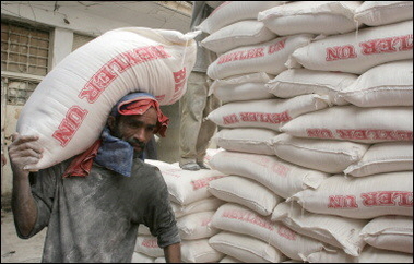 An Iraqi worker carries bags of government wheat rations in the Shiite Baghdad suburb of Sadr City.