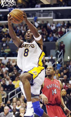 Los Angeles Lakers' Kobe Bryant (L) scores two of his 81 points as Toronto Raptors' Joey Graham looks on during the second half of their NBA game in Los Angeles January 22, 2006. Bryant's 81 points set a personal career high, and the performance is the second-highest single-game scoring total in NBA history.