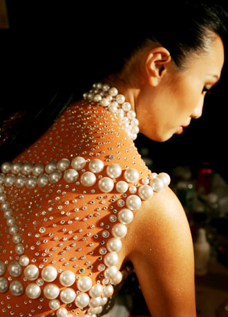 A model with hundreds of pearls and sequins glued to her body waits for her makeup to dry before a Chinese New Year celebration MAC fashion show in New York February 2, 2006. The elaborate makeup applications took up to eight hours to apply on the topless models who then posed in front of backdrops at a cocktail party. The show kicks off Fashion Week which starts on Friday.
