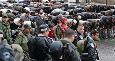 Israeli policemen watch as Palestinians pray on the street near Al-Aqsa compound in Jerusalem's Old city February 3, 2006.