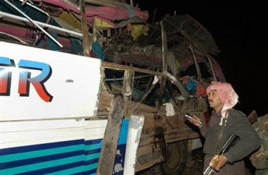 An unidentfied Pakistani police officer looks at passenger bus damaged by a bomb explosion, Sunday, Feb 5, 2006 in Kolpur, about 18 kilometer southeast of Quetta, Pakistan.