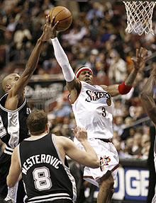 Philadelphia 76ers guard Allen Iverson (R) shoots under pressure from the San Antonio Spurs forward Bruce Bowen (L) and Spurs center Rasho Nesterovic during the second quarter of their NBA game in Philadelphia February 15, 2006. Iverson scored 42 points in the 76ers' 103-100 overtime win over the San Antonio Spurs.